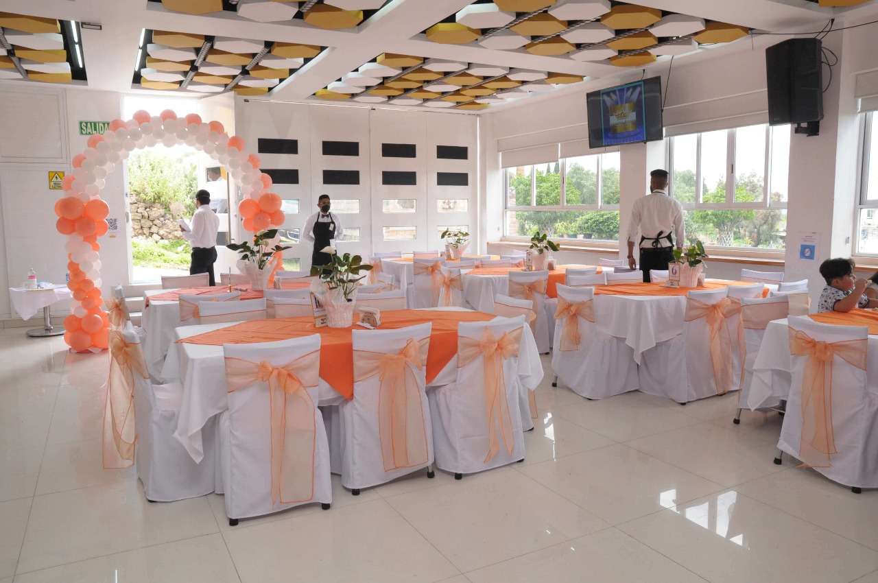 Salón con mesas decoradas con cintas naranjas